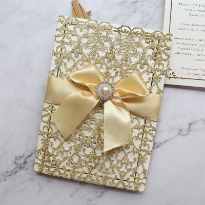 China Europe personalized luxury gold glitter lace laser cut wedding invitations with jewel and satin bow for sale