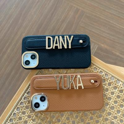 China Business Wristband Shockproof Holder Striped DIY Metal Letters Custom Name Phone Case For iPhone 14 Pro Max Leather Phone Cover for sale