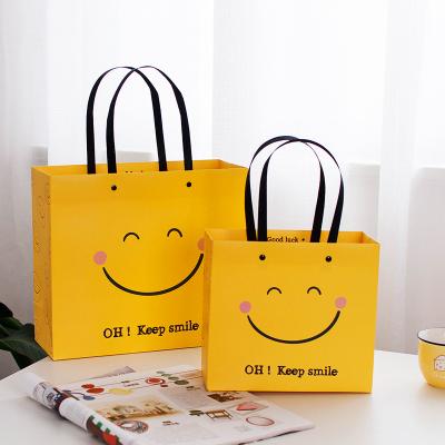 China Recyclable Handbag Face Business Gift Paper Bag Clothing Kraft Paper Bag Simplicity Smile Festival for sale