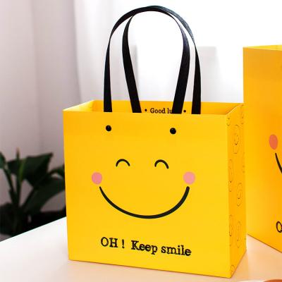 China Recyclable Handbag Face Business Gift Paper Bag Clothing Kraft Paper Bag Simplicity Smile Festival for sale