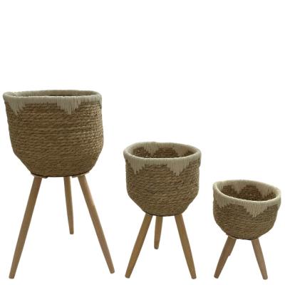 China Modern 2023 new design grass rope wicker planter  flowerpot with three timber toe and Plastic lining for indoor/outfoor for sale