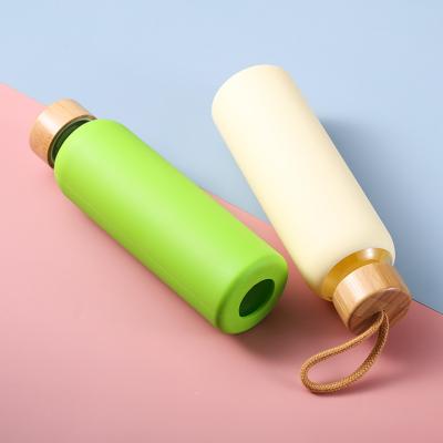 China Sustainable Eco-friendly Creative Glass With Silicone Wooden Sleeve Solid Color Rope Lid Protective Glass Bottle for sale