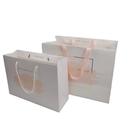 China Custom Recycled Materials 210g White Card Recycled Hot Foiled Logo Ribbon Handle Clothes Paper Bag With for sale