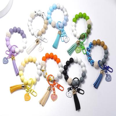 China Faux Fur Ball Pompom Chains Wholesale Fashion Silicone Printing Elastic Wood Bead Smile-face Charm Key Chain Pendant With Leather Tassel for sale