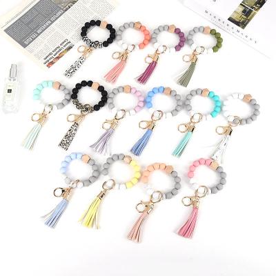 China Free Sample Faux Fur Ball Pompom Chains Solid Portable Wooden Beaded Silicone Bead Bracelet Key Chain Bracelet Keychain With PU Tassel for sale