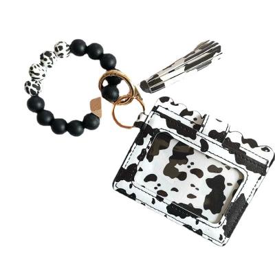 China Faux Fur Ball Pompom Chains Black Cow Print Silicone Bead Bracelet Key Chain PU Card Holder Wallet Wristlet Key Ring With Tassel for sale