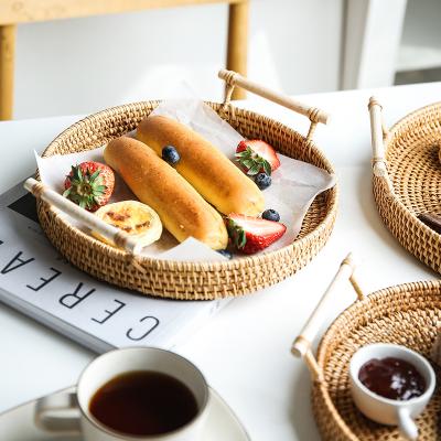 China Sustainable Handmade Rattan Breakfast Food Serving Tray Fruit Bread Basket Picnic Wicker Snack Kitchen Storage Container With Wooden Handle for sale