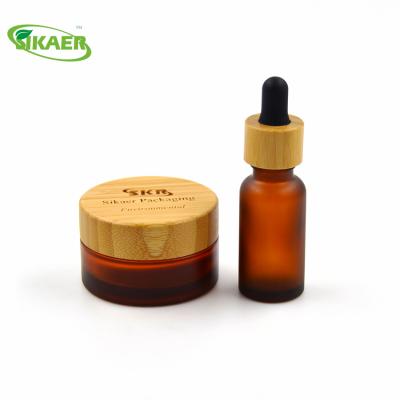 China Recyclable Material Organic Amber Essential Oil Glass Bottle With Bamboo Cap Cosmetic Packaging for sale