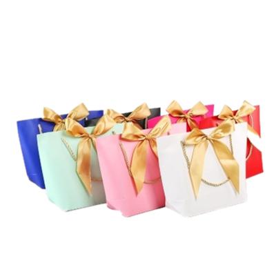 China Disposable Custom Logo Tote Shape Retail Paper Gift Bag With Bow for sale