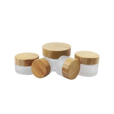 China Eco-friendly bamboo cap with wooden top small wide mouth trim 50ml cosmetic body butter gel cream frosted glass jar 50ml with bamboo wooden set lid for sale