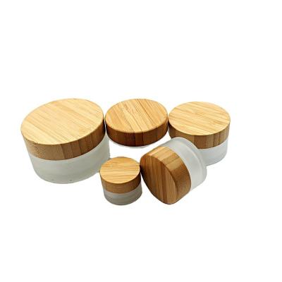 China 15g 30g 50g 100g Cosmetic Clear Cream Lotion Jar Cosmetic Environmental Frosted Glass Container With Wooden Cap Custom Logo for sale