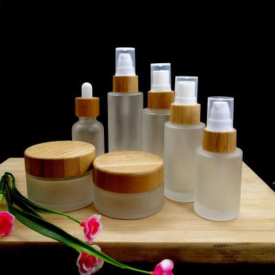 China Personal Care Garfish With Bamboo Frost Clear Lids Glass Lotion Pump Bottle With Bamboo Lid for sale