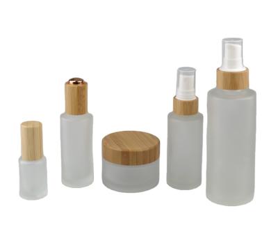 China Personal Care Frost Clear Lotion Glass Pump Bottle With Bamboo Lid for sale