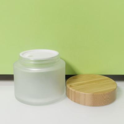 China Luxury Custom Cosmetic Packaging 200g Empty Clear Frosted Glass Jar With Bamboo Lids Skin Care Cosmetic Packaging for sale