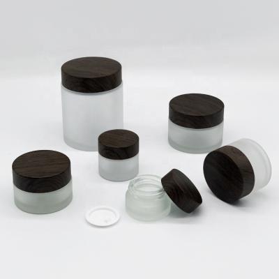 China 5g cosmetic 10g 15g 30g 50g 100g frosted cosmetic cream glass jar with dark brown plastic wood grain lid for sale