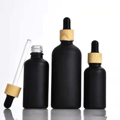 China 5ml 10ml 15ml 20ml 30ml 50ml 100ml cosmetic matte black dropper glass bottle with bamboo lid for cosmetic packaging for sale