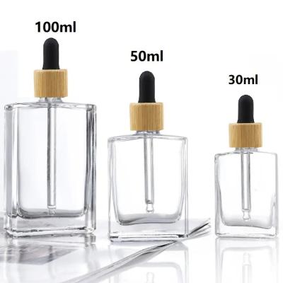 China Popular Empty Clear Flat Square Rectangle Cosmetic 1oz 30ml Dropper Oil Serum Cosmetic Glass Bottle 30ml With Bamboo Cap for sale