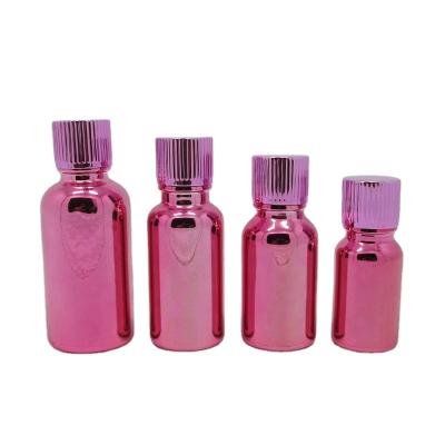 China Recyclable Material Wholesale Empty Electroplating Rose Essential Oil Red Cosmetic Glass Bottle With Inner Plug And Pink Aluminum Cap for sale