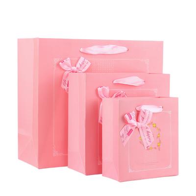 China Recyclable various size alternative pink color bowknot paper bag for girl gift packaging with custom logo and handles for sale