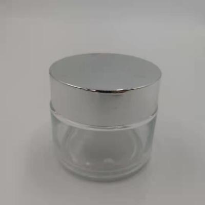 China MSDS Clear 100g Glass Cream Jar With Shiny Silver Cap White Lid Mask Mud for sale