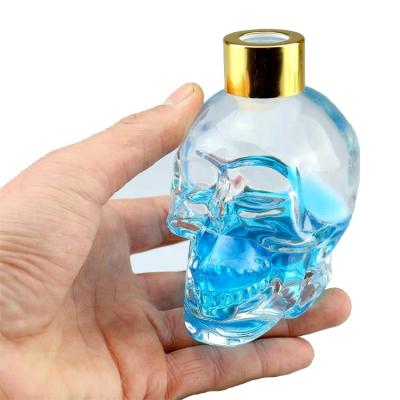 China Perfume 2018 hot sale skull shape aromatherapy glass bottle with gold paint plated cap for sale