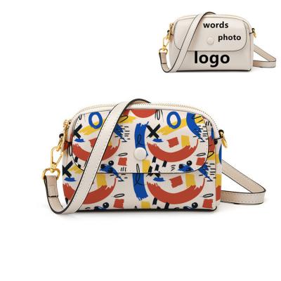 China Adjustable Shoulder Strap OEM Branded Girls Custom Cross Logo Graffiti Print Women Shoulder Bag - Body Bag Zipper Real Leather Luxury Small Purse for sale