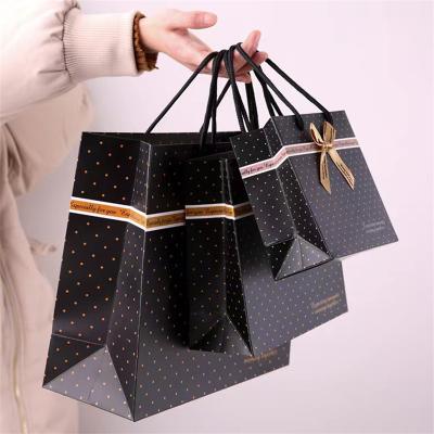 China Recycled materials black color print bowknot paper bag hand-held shopping bag manufacturers direct LOGO advertising bag for sale