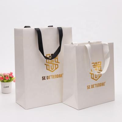 China Recyclable Embossing Luxury White Relief Logo Ivory Board Paper Gift Bag For Clothing Boutique Shopping With Satin Handle for sale