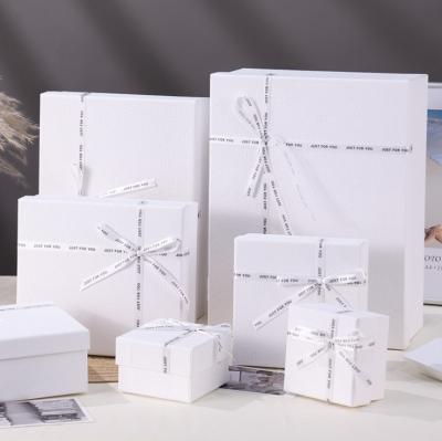 China Handmade square white textured gift box set small white wedding invitation paper packaging gift box bag setwith large ribbon decoration for sale