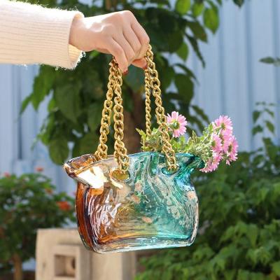 China Modern Wholesale Two Colored Luxury Art Glass Handbag Flower Vase With Metal Belt Decor Wedding Home Decoration for sale