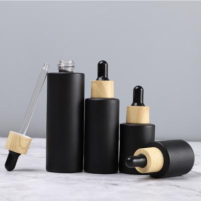 China Hot Selling Cosmetic 20ml 30ml 50ml 60ml 100ml Frosted Matte Black Essential Oil Glass Pipette Dropper Bottle With Wood Grain Caps for sale