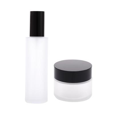 China Cosmetic empty cosmetic packaging sets clear frosted cream jar with black lid glass bottle for toner lotion for sale