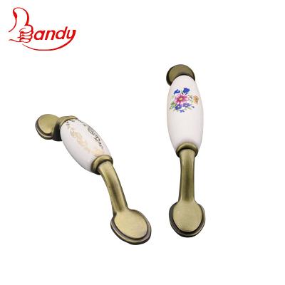 China Manufacture Foshan Round Ceramic Zamak Traditional Zinc Alloy Leg Bar With Flower Pattern Sideboard Cupboard Wardrobe Pull Handles for sale