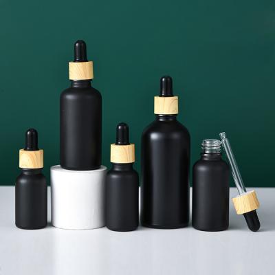 China Custom Printing Matte Black Cosmetic Packaging Essential Oil Glass Bottle 5 10 15 20 30 50 100ml With Wood Grain Dropper for sale