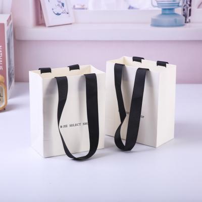 China Recycled Materials Custom Printed Tote Paper Gift Bag With Logo Kraft Paper Carrier Clothes Packaging Bag for sale