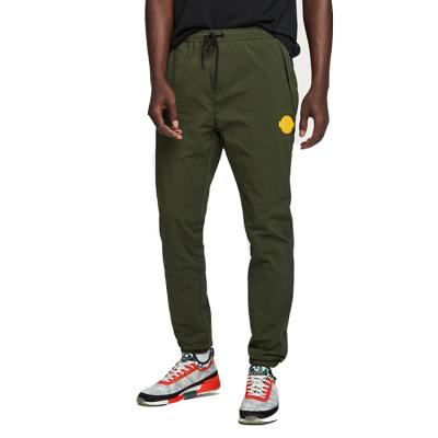 China Zipper Pocket Nylon Soft Stretch Elasticated Leg Olive Green Rubber Logo Print Mesh Linied Joggers Pants for sale