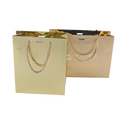 China Biodegradable custom logo high quality gold foil stamping matte shopping paper bag with paper ribbon handle bag en for sale