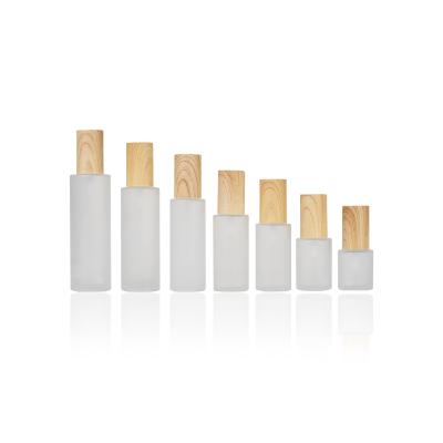 China Eco-friendly Recyclable Wholesale Cosmetic Sets Flat Shoulder Frosted Glass Liquid Lotion Bottle With Bamboo Wooden Lotion Pump Cap for sale