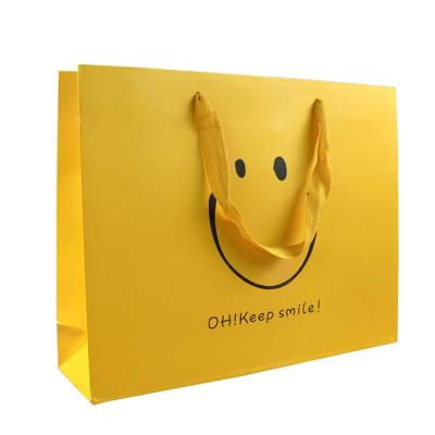 China Recycled Materials New Arrival Simple Elegant Folding Yellow Paper Bag With Custom Printing Logo Shopping Clothing Garment Paper Bag for sale