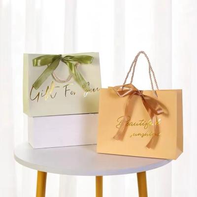 China Recyclable Chinese factory custom printed bow paper bag with logo gift bag with ribbon handle handwork for sale