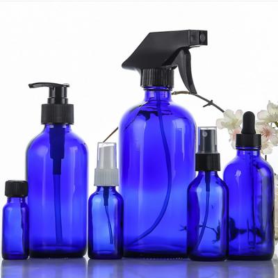 China Refillable Empty Personal Care Cobalt Blue Storage Containers Glass Boston Round Bottle With Black Treatment Pump for sale