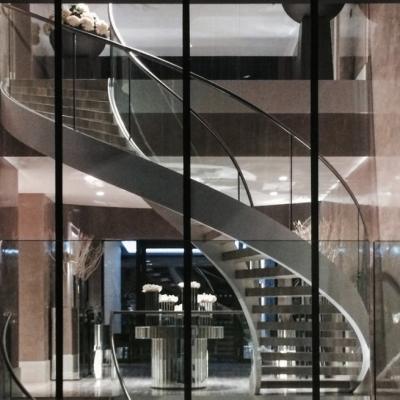 China Contemporary Lobby Stair Glass Enclosure Steel Plate Double Curved Staircase for sale