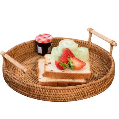 China Sustainable Handwoven Round Organizer Rattan Food Storage Tray With Wooden Handle for sale