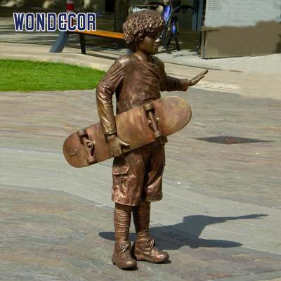 China A bronze metal art sculpture of a boy holding a skateboard outdoors for sale