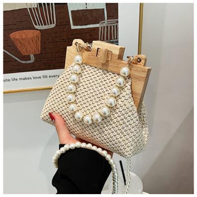 China Wooden Frame Lock Messenger Chain Shoulder Bag Seaside Beach Waterproof Braided Purse Pearl Handbag Fashion Cosmetic Bag for sale