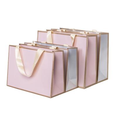 China Recyclable Custom Paper Tote Bag Waterproof Luxury Garment Packaging Bag With Satin Silk Ribbon for sale