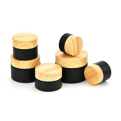 China Refillable 1oz Skin Care Jar 5g 10g 50g Empty Black Glass Cosmetic Cream Jar Refillable Cosmetic Jar With Wood Grain Cover for sale