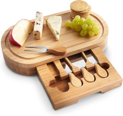 China Sustainable Oval Bamboo Cheese Cutting Board Set with Cutlery 4 Accessories in Slide Drawer Pizza Vegetable Kitchen Cutting Boards for sale