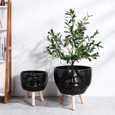 China Creative New Arrival Design Popular Modern Indoor Decorative Black Floor Flower Pot Face Plant Pots With Foot Wooden Stand for sale