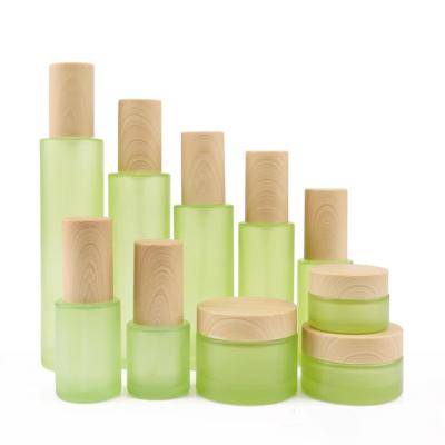 China Hot Sales Cosmetic Cosmetic Packaging Set Natural Wood Grain Lid Green Frosted Glass Lotion Bottle With Pump for sale